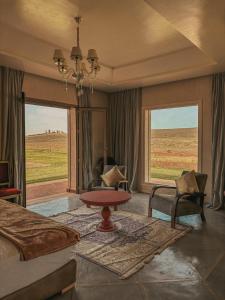 a bedroom with a bed and a table in front of a window at Domaine Golfique Lamrah - Pavillon 5 Chambres in Marrakech +22 photos