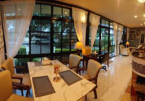 a dining room with a table and chairs and windows at Chill House in Pak Chong