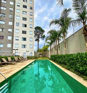 a swimming pool in front of a building with palm trees at Seu cantinho in Sao Paulo