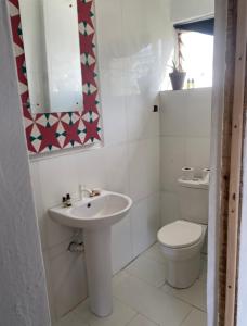a white bathroom with a toilet and a sink at Popbeachclub Suites ilashe in Ibasa