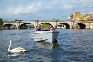 two people on a boat in the water with a swan at the crown loft ensuite luxury accomodation in Kingston upon Thames