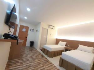 a hotel room with two beds and a flat screen tv at D&M Travellers Inn in Plaridel