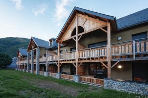 Cette grande maison en rondins est entourée d'une terrasse. dans l'établissement Magnifique appt NEUF 6 pers - vue montagne St Lary - curistes ok, à Vielle-Aure