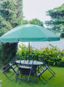 einen Tisch und Stühle unter einem blauen Schirm in der Unterkunft Arusha Kwetu Villa in Sokon