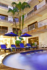 a pool in a hotel with blue chairs and umbrellas at Baan Boa Resort in Patong Beach