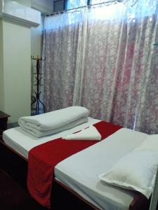 Un dormitorio con dos camas con sábanas rojas y blancas. en Hotel City Crown Lamahi Dang, en Namāi