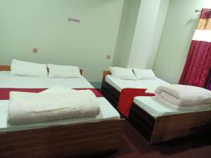 una habitación con dos camas con sábanas blancas en Hotel City Crown Lamahi Dang, en Namāi
