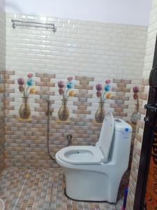 baño con aseo con flores en la pared en Hotel City Crown Lamahi Dang, en Namāi