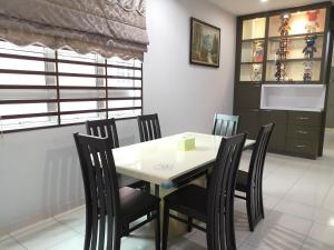 una sala da pranzo con tavolo e sedie bianchi di 优雅聚民宿 a Kampong Kuala Punti