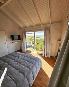 a bedroom with a large bed and a large window at Dique Los Molinos Exclusiva casa vista al lago in Cordoba