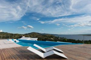 a swimming pool with two white chairs on a patio at Dique Los Molinos Exclusiva casa vista al lago in Cordoba