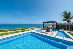 a swimming pool with a view of the ocean at Shama Apartment beach front in Isla Mujeres