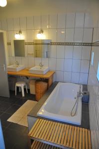 een grote badkamer met 2 wastafels en een bad bij A côté de l'Epicerie in Bonsin