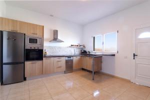 a kitchen with wooden cabinets and a stainless steel refrigerator at Casa Aloe in Teseguite