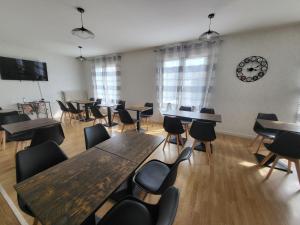 a room with tables and chairs and a clock on the wall at Hôtel Le Lyon Vert Commentry in Commentry