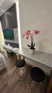 a room with a table with two stools and pink flowers at Pollux Habibie batam in Batam Center +6 photos