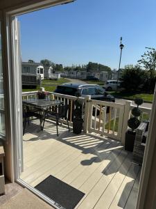 a wooden deck with a table and a dining table at Acres Corner Retreat Inc Hot tub at Tattershall Lakes Country Park in Tattershall