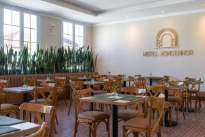 a dining room with tables and chairs and plants at Hotel Monsenhor in São Sebastião do Paraíso