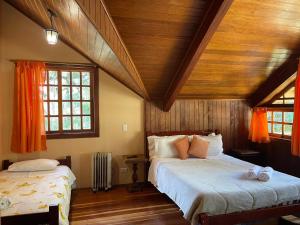 two beds in a room with wooden ceilings and windows at Suítes Monte Belo in Campos do Jordão