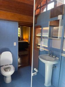 a blue bathroom with a toilet and a sink at Suítes Monte Belo in Campos do Jordão