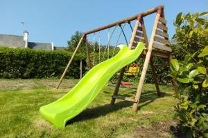 a playground with a green slide in a yard at Maison avec jardin proche du centre et des plages in Carantec