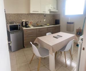 a kitchen with a table and chairs and a sink at Bienvenue chez Virginie in Pontorson