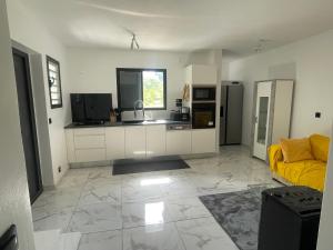 a living room with a yellow couch and a kitchen at Villa KENCYAPATRICIA in Sainte-Anne