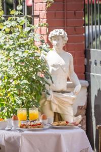 a table with a statue of a woman with food and orange juice at Nafsimedon Hotel in Nafplio