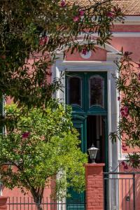a green door on a pink building with a tree at Nafsimedon Hotel in Nafplio