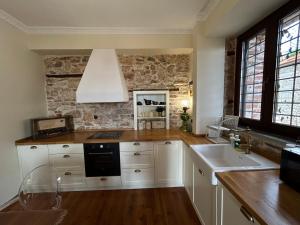 a kitchen with white cabinets and a stone wall at Αρχοντικό Νόνη in Mileai +22 photos