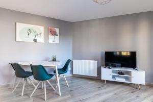 a dining room with a table and chairs and a tv at L'aigle, Bel appartement Proche centre et parking in Grenoble