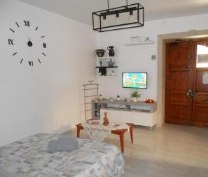 a bedroom with a clock on the wall and a table at MAISON ISOLA DI ORTIGIA in Siracusa