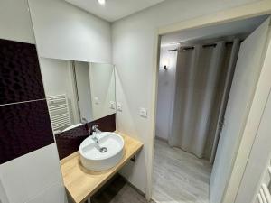 a white bathroom with a sink and a mirror at Domaine des 5 Roses - Rose Rouge in La Guierche +8 photos