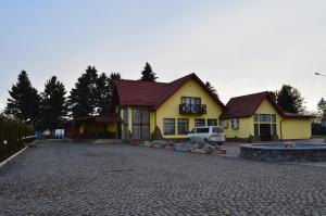 Starokostyantyniv的住宿－Hotel Fiyesta，一座黄色的房子,前面有一辆汽车