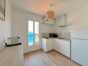 eine Küche mit weißen Schränken und einem Fenster in der Unterkunft "Casa Mia" - Sea View - Old Town House - 4 persons in Menton