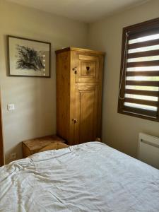 a bedroom with a bed and a wooden cabinet at Marmotton in Megève
