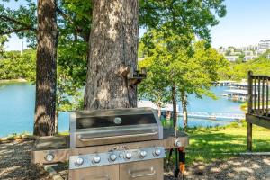 a grill in front of a tree next to a river at Artilla Cove Cabin 8- Lakeview- BBQ Area- Pool in Branson