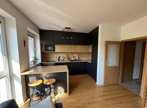 ブラチスラヴァにあるGarden-view Apartment near City Centerのキッチン(黒いキャビネット、カウンター、スツール付)