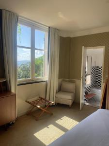 a bedroom with a bed and a chair and a window at Hotel Ermitage in Saint-Tropez