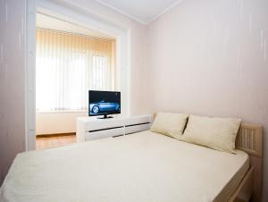 a white bedroom with a bed and a tv at Apartlux Vernadskogo Superior in Moscow
