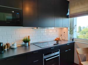 kuchnia z czarnymi szafkami i talerzem jedzenia w obiekcie 7th Floor Apartment Mokotów w Warszawie