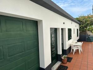 ein grünes Garagentor an einem Haus mit einem Tisch in der Unterkunft Refúgio dos Prazeres - Madeira Inn Group in Prazeres