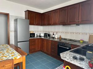 eine Küche mit Holzschränken und einem Edelstahlkühlschrank in der Unterkunft Refúgio dos Prazeres - Madeira Inn Group in Prazeres
