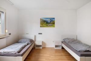 Habitación con 2 camas, paredes blancas y suelo de madera. en 4 x Wohnungen in Waiblingen, en Waiblingen