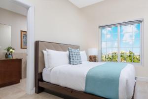 a bedroom with a large bed with a window at One Grace Bay Townhomes Unit 205 in The Bight Settlements
