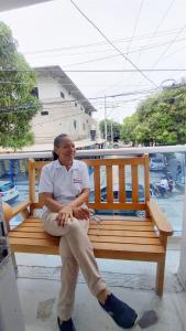 a woman sitting on a wooden bench at Hotel Tranvia in Santa Marta