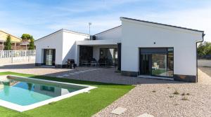 a white house with a swimming pool in front of it at Casa Rural La Yesería Alcocer in Sacedón