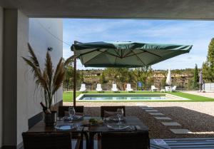 a patio with a table with a green umbrella at Casa Rural La Yesería Alcocer in Sacedón