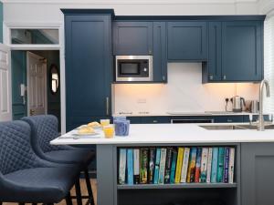 eine Küche mit blauen Schränken und einer Theke mit Büchern in der Unterkunft Sailors Rest in Dartmouth