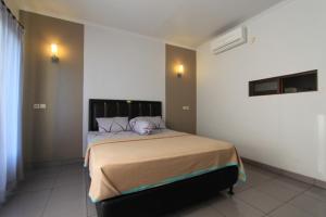 a bedroom with a large bed in a room at De Dukuh Guest House in Kuta